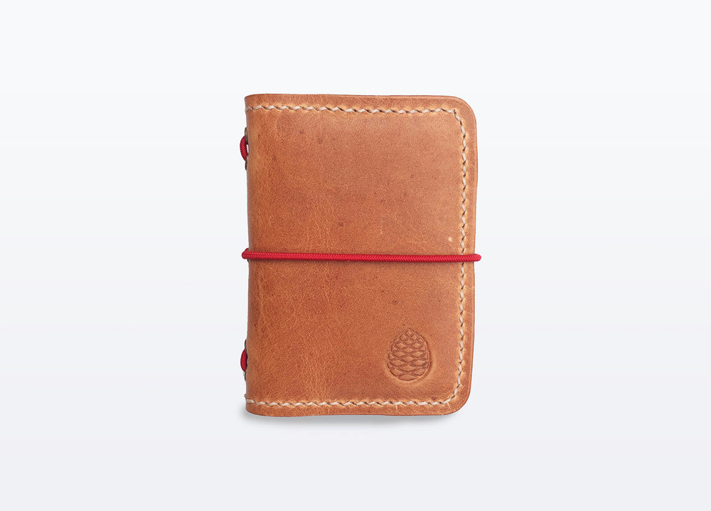 Leather Card holder wallet, hand stitched in small batches in Sheffield, UK. Pine Cone Logo imprinted on bottom right corner and a red elastic rope closure.