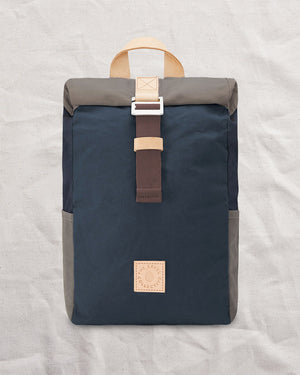 Front of the Navy & Stone roll top backpack: navy waxed canvas body, stone roll top and stone side pockets
