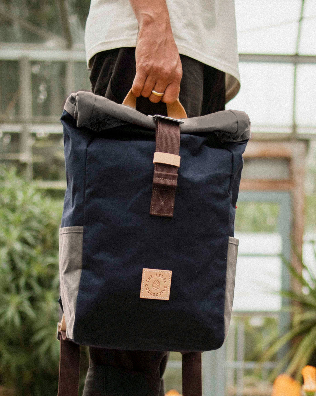 Natural leather grab handle on the Navy & Stone roll top backpack with stone roll top