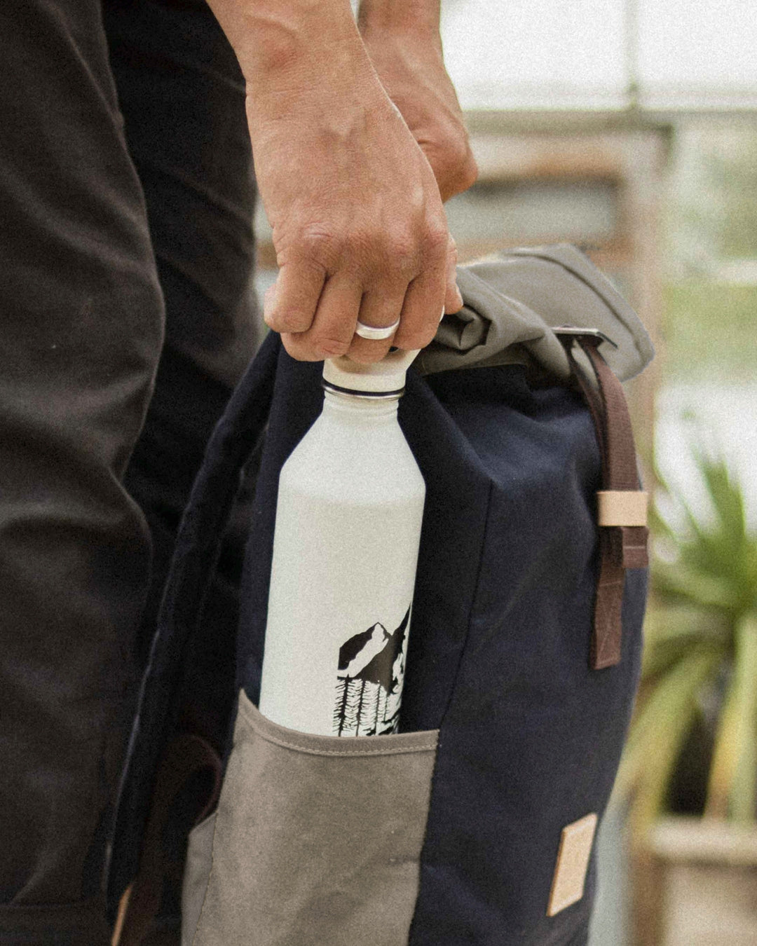 Water bottle in the stone side pocket of the Navy & Stone roll top backpack