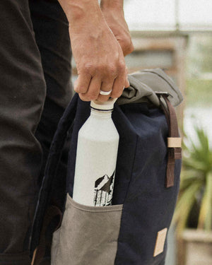 Water bottle in the stone side pocket of the Navy & Stone roll top backpack
