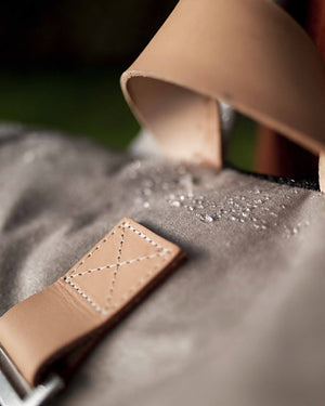 Water beading on the stone waxed canvas roll top beside the natural leather handle