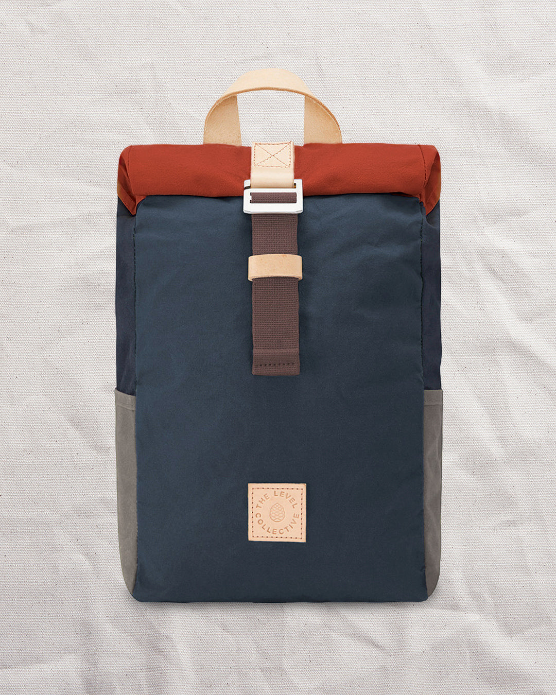 Front of the Wild One Navy roll top backpack: navy waxed canvas body, rust roll top and stone side pockets