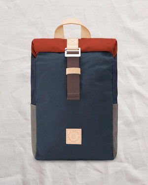 Front of the Wild One Navy roll top backpack: navy waxed canvas body, rust roll top and stone side pockets