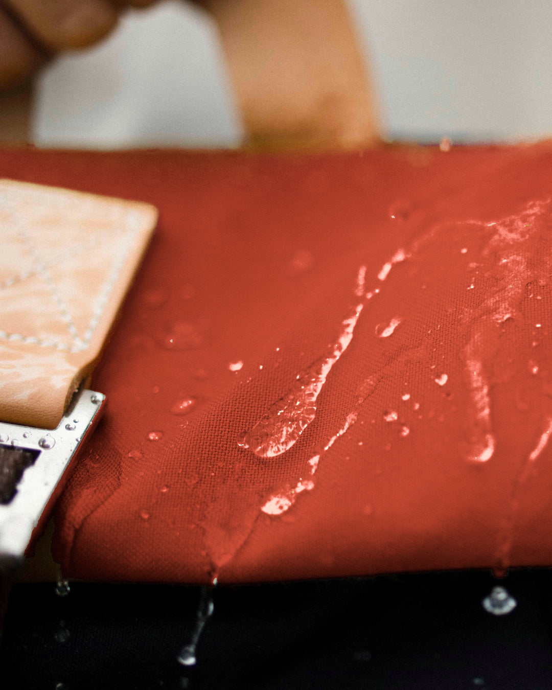 Water beading on the rust roll top of the Wild One Navy roll top backpack, weatherproof waxed canvas