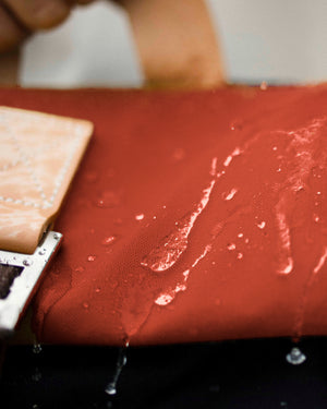 Water beading on the rust roll top of the Wild One Navy roll top backpack, weatherproof waxed canvas
