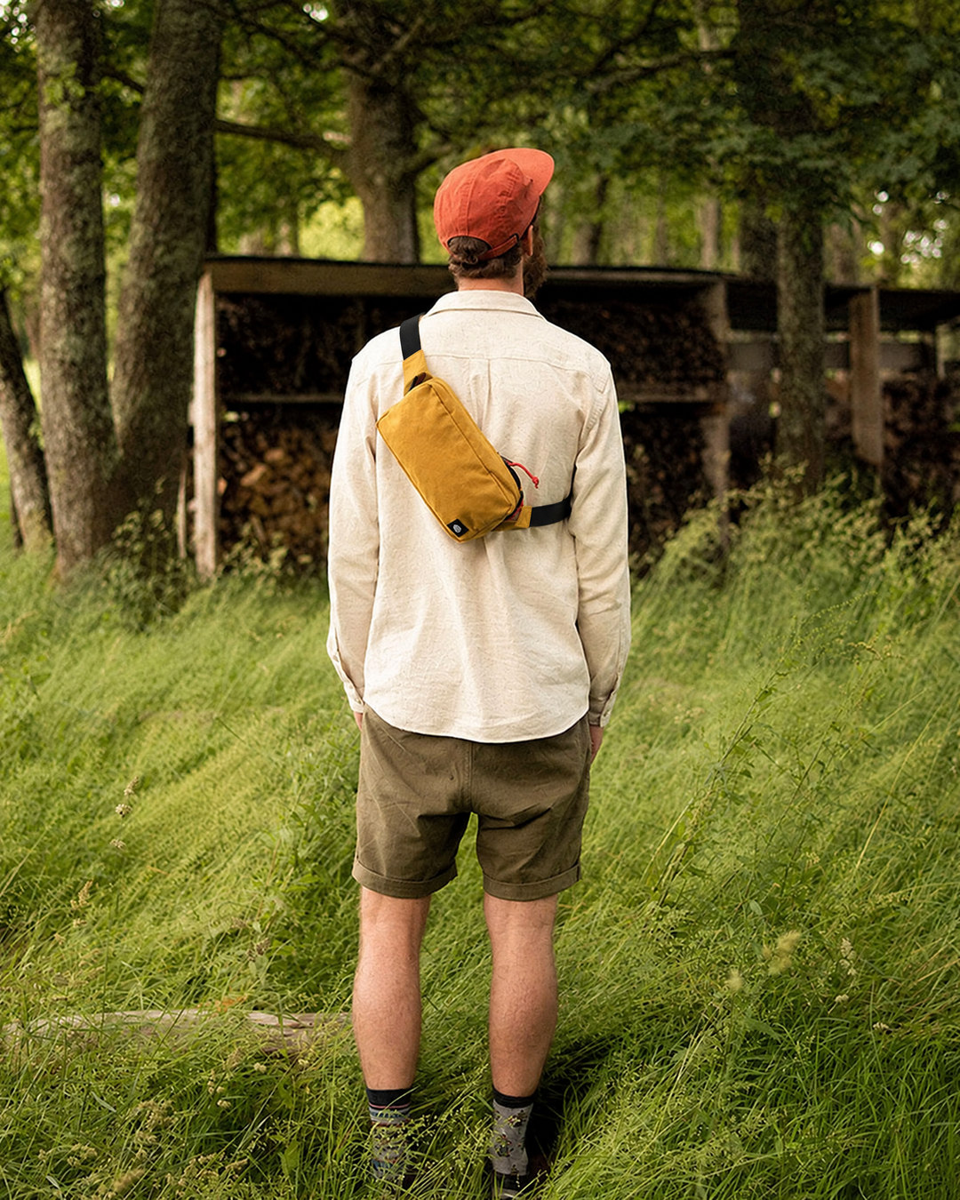 The Scout in Mustard worn cross body on the back in a meadow, black webbing strap