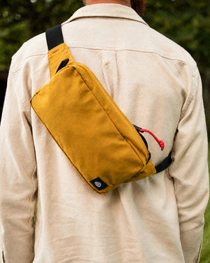 Close up of The Scout in Mustard waxed cotton worn across the back with black strap