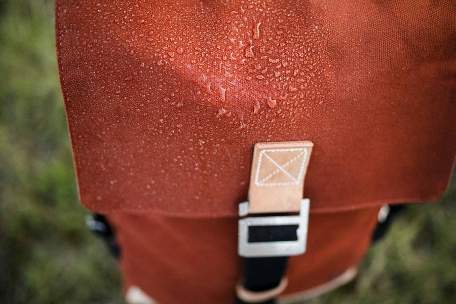 Logan backpack in Rust with rain beading on the waxed cotton